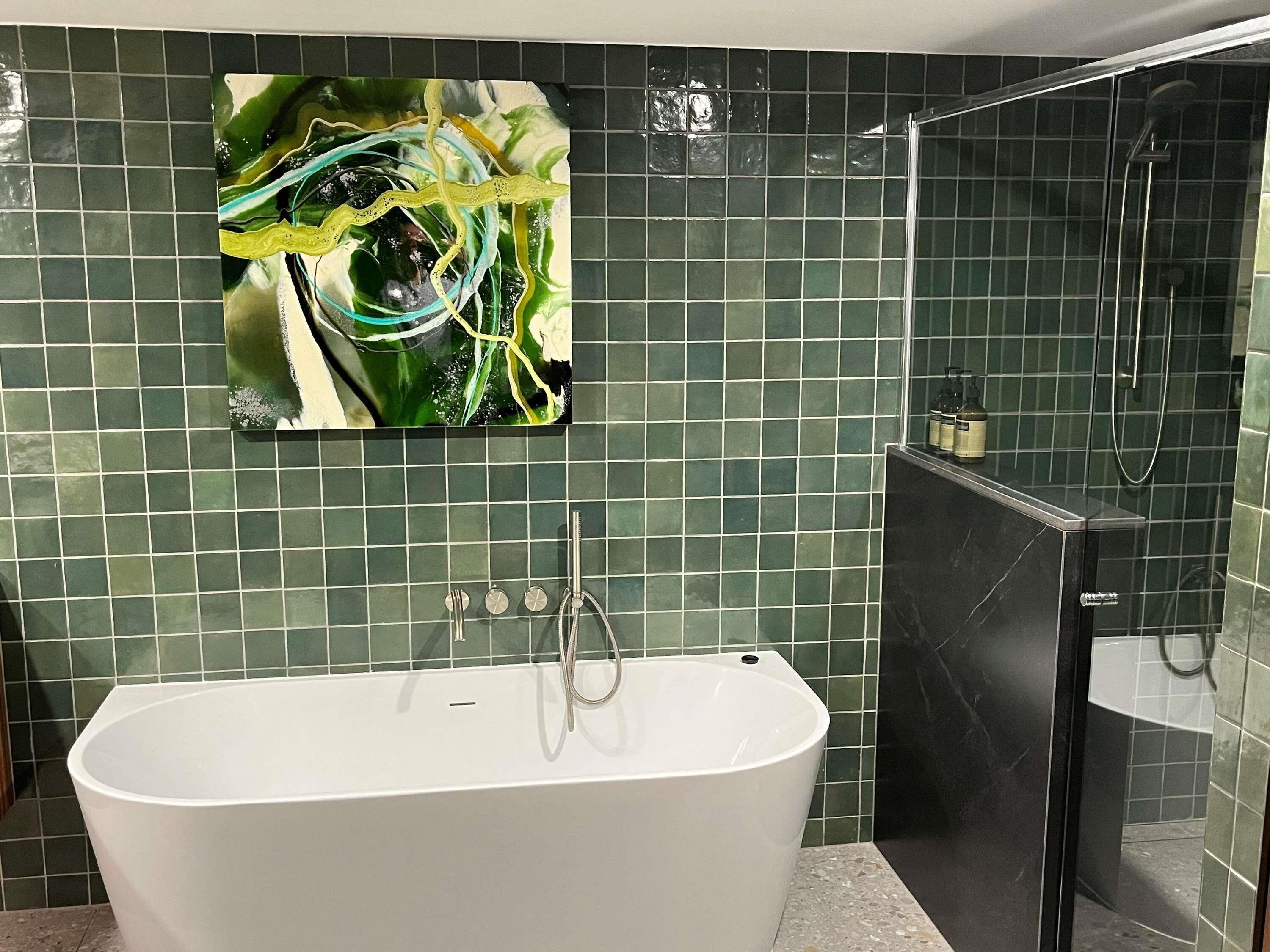A bathroom with a freestanding bathtub, a glass shower enclosure, and a green-tiled wall.