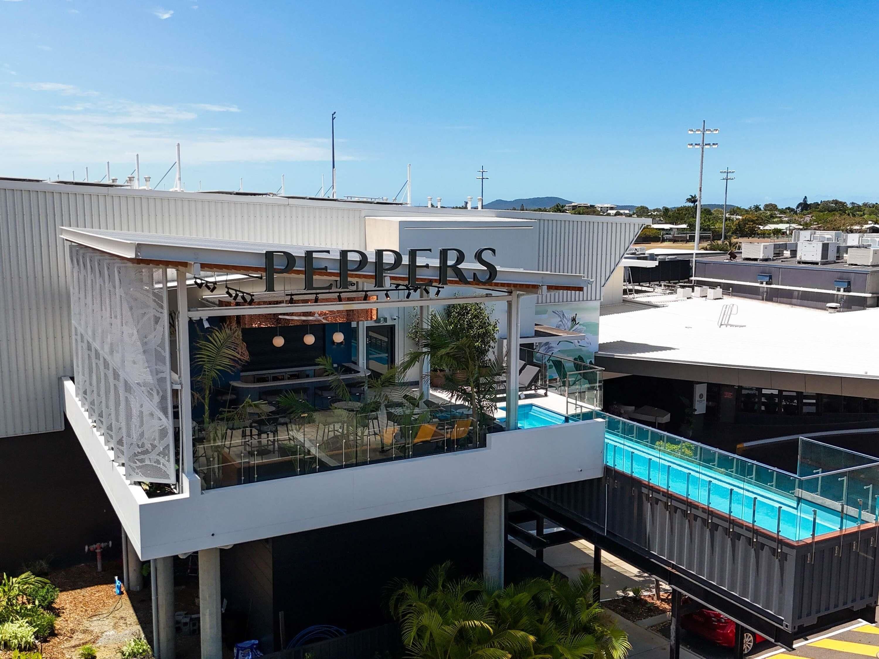 Um restaurante no terraço chamado 'PEPPERS' com área externa, piscina e vista da região.
