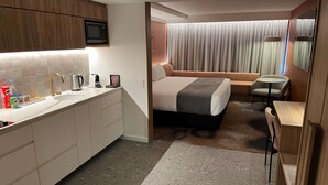 A modern hotel room with a kitchenette, a bed, a desk, and a bathroom. - Peppers Gladstone (Barney Point)