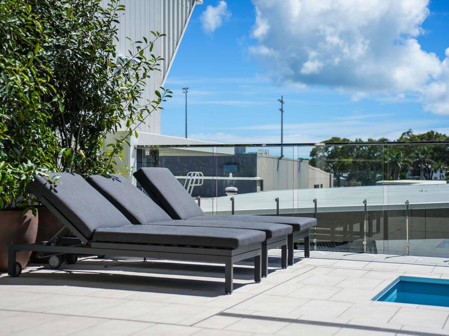 A rooftop pool area with lounge chairs and a small pool.