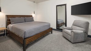 A bedroom with a bed, a chair, a ceiling fan, a mirror, and a TV. - Vizcaya #9 - Moab's Newest Luxury Rental (Moab)