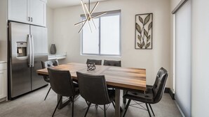 A modern kitchen with a stainless steel refrigerator, a built-in water dispenser, and a wooden dining table with four chairs. - Vizcaya #12 - Moab's Newest Luxury Rental (Moab)