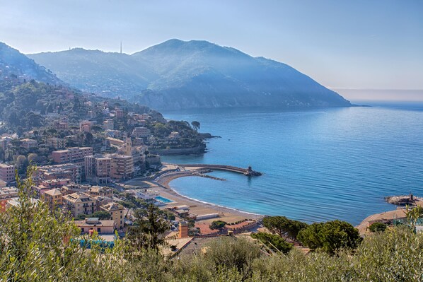 A coastal town with buildings along the waterfront, a bridge, and a mountainous backdrop. - Wonderful Villa With Sea View Terrace In Mulinetti (Recco)