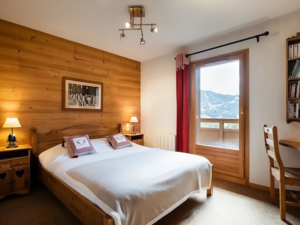 Une chambre à coucher aux murs lambrissés, avec un lit, deux lampes de chevet, une fenêtre donnant sur un beau paysage et une bibliothèque.
