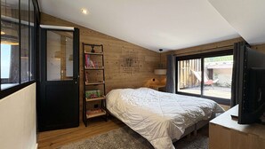 A bedroom with a bed, a bookshelf, a desk, and a TV. - Renovated duplex in Les Orres, 3 rooms for 8, WiFi, pets allowed (Les Orres)