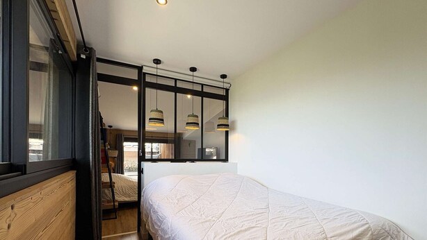 Una camera da letto con un letto, pavimento in legno, una finestra e una scala che conduce a un livello superiore.