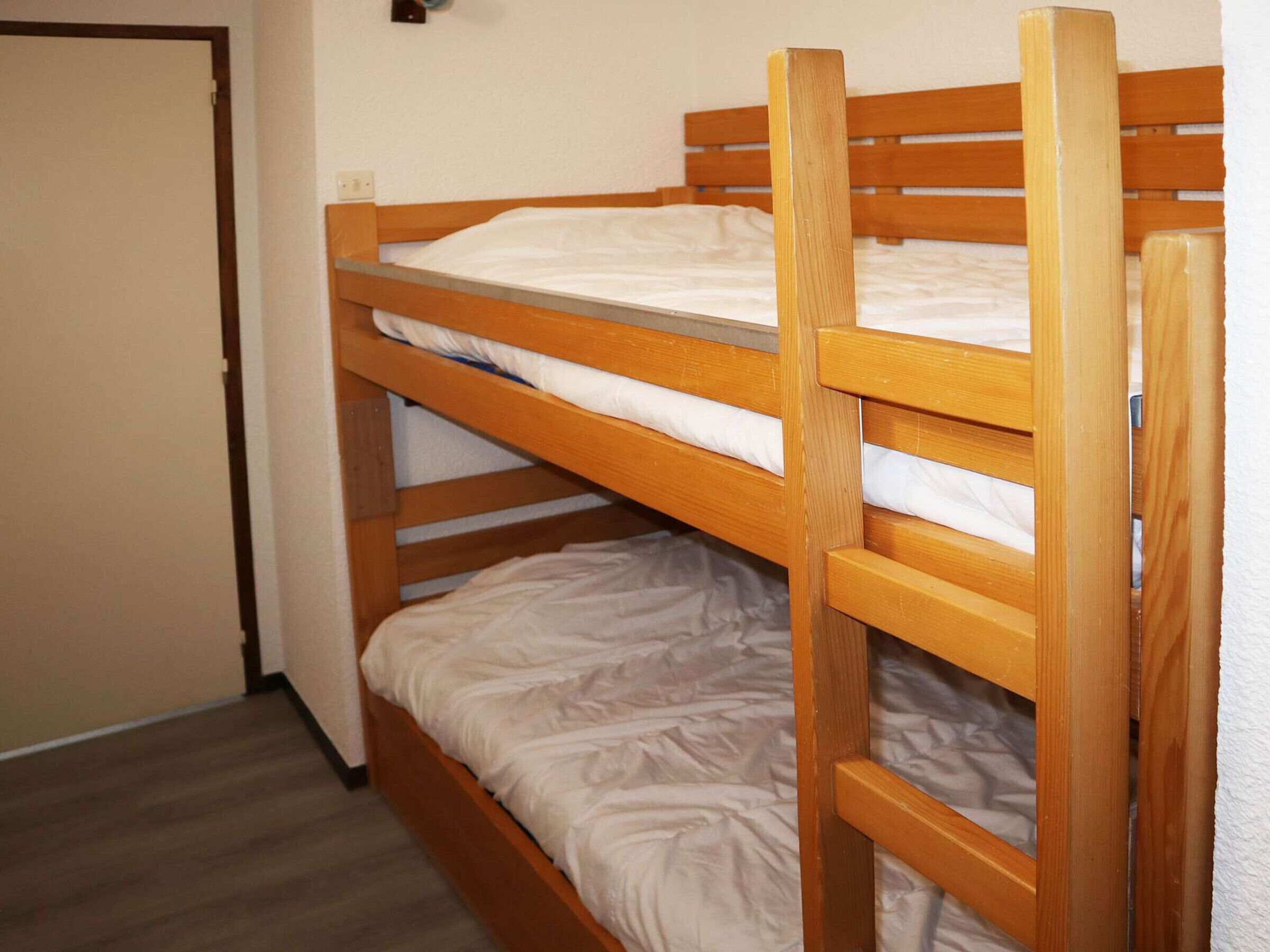 A bunk bed with two levels, a wooden headboard, and a plain wall.
