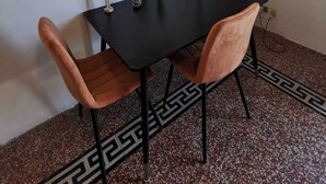 A dining area with a black table, two wooden chairs, and a painting of red flowers on the wall. - 2 Bedroom Apartment in Palermo (Palermo)