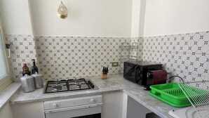 A compact kitchen with a gas stove, oven, microwave, and a sink. - 2 Bedroom Apartment in Palermo (Palermo)