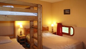 A room with two bunk beds, each with a nightstand and a lamp. There is a window with red curtains and a picture on the wall. - Cozy 2-Bedroom Apartment for 6 with Mountain View, Balcony, and Ski-in/Ski-out Access (Les Orres)