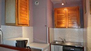 A compact kitchen with wooden cabinets, a sink, and a stove. - Cozy 2-Bedroom Apartment for 6 with Mountain View, Balcony, and Ski-in/Ski-out Access (Les Orres)