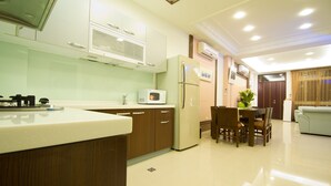 A modern kitchen with wooden cabinets, a built-in microwave, and a refrigerator. There is a dining area with a table and chairs. - Kuan-Pin B&B (Wujie)