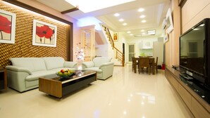 A modern living room with a sofa, coffee table, and TV. There is a staircase leading to another room. - Kuan-Pin B&B (Wujie)