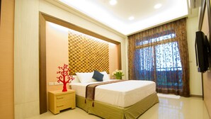 A modern hotel room with a large bed, a nightstand, a decorative tree, and a window with curtains. - Kuan-Pin B&B (Wujie)