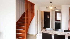 Un coin repas avec un escalier en bois, une table entourée de chaises et un luminaire suspendu.