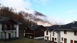 Une rangée de chalets, avec une vue sur les montagnes en toile de fond, qui présentent un mélange d’architecture moderne et traditionnelle.