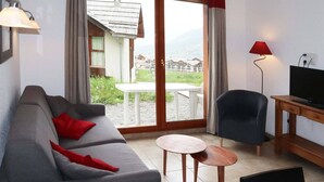 Un salon avec un canapé, une table, une chaise et un téléviseur.
