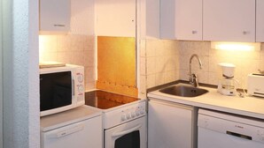 Une cuisine compacte équipée d’un four à micro-ondes, d’une cuisinière, d’un four, d’un évier et d’une machine à café Bosch.