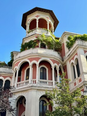 A multi-story building with a red and white facade, featuring arched windows and balconies. - Charming studio apartment with panoramic views in Rome (Roma)