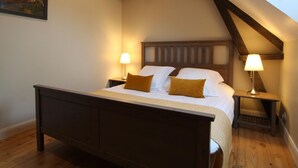 A bedroom with a wooden bed, two bedside tables with lamps, and a sloped ceiling.
