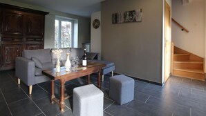 A spacious living area with a dining table, grey sofas, and a staircase.