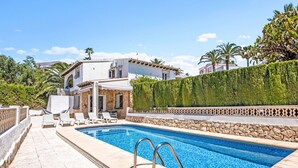 A pool area with a stone deck, lounge chairs, and a white building with a stone facade. - Vacation home Adinga by Interhome (Moraira)