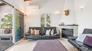 A modern living room with a leather sofa, a fireplace, and a glass door leading to a balcony. - Vacation home Adinga by Interhome (Moraira)