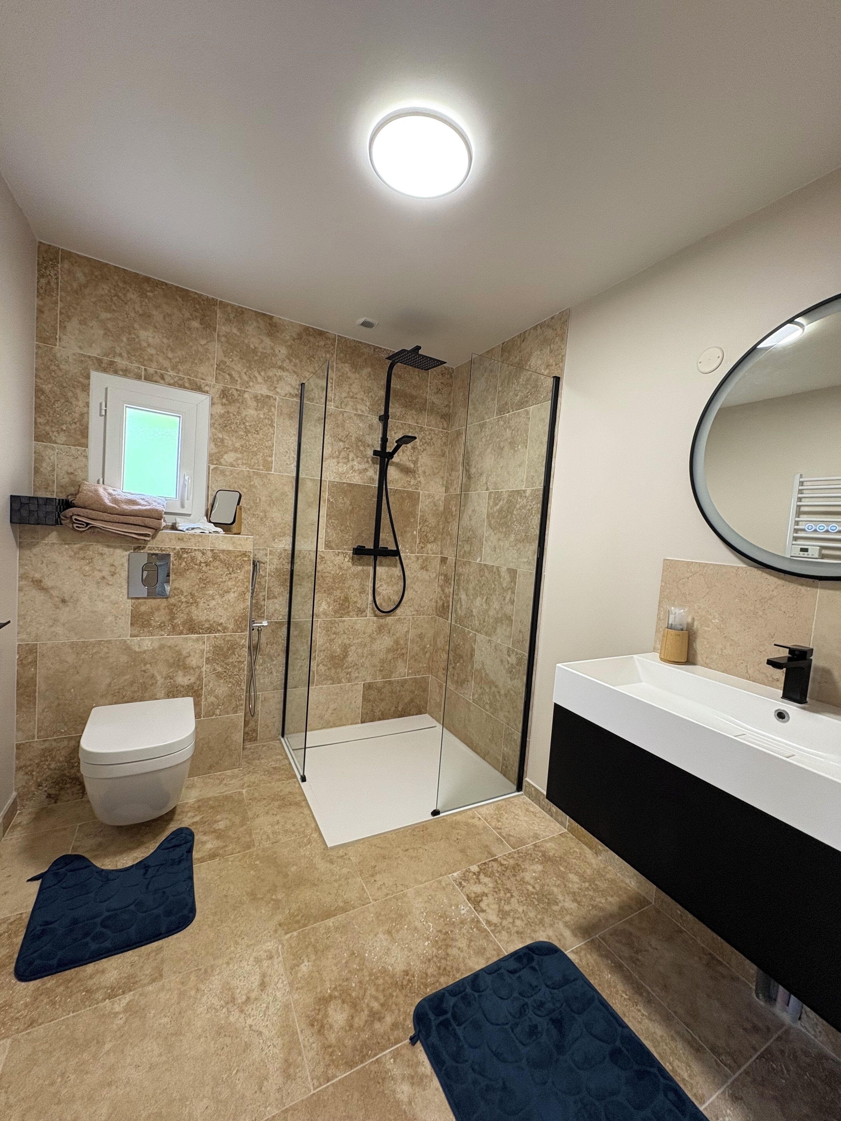 A modern bathroom with a shower, toilet, and sink.