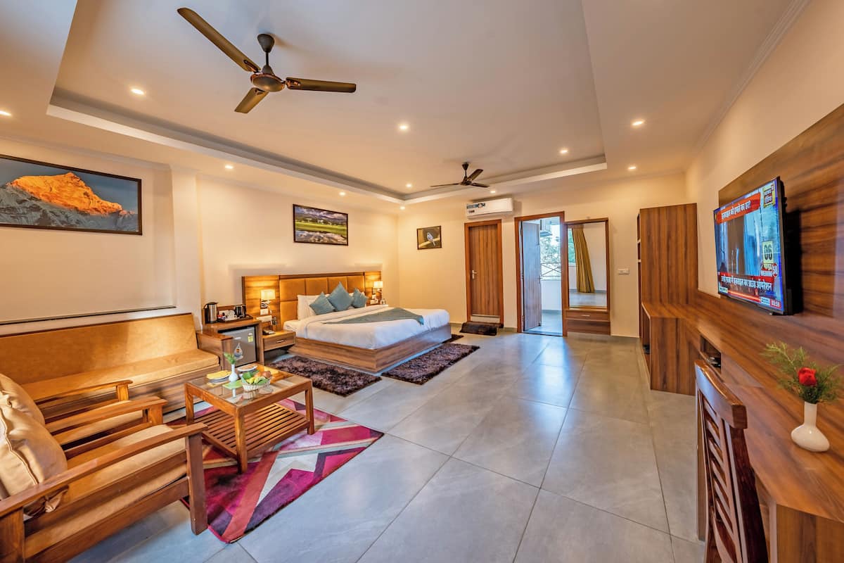A modern hotel room with a bed, a sofa, a TV, and a ceiling fan.