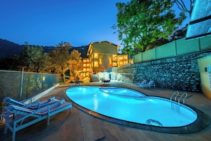 Une piscine avec des chaises longues et un mur en pierre.
