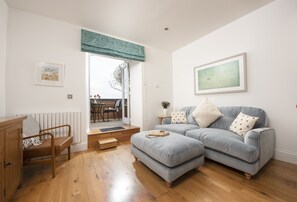 Un salon avec un canapé, une chaise en bois, une petite table et un radiateur.