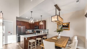 Een moderne keuken met houten kastjes, roestvrijstalen apparatuur en een centraal eiland met krukken.