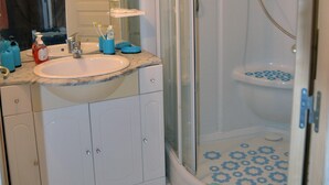 Een badkamer met wastafel, spiegel en douche.