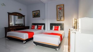 A hotel room with two beds, a dresser, a mirror, and artwork on the walls. - Hotel O Maluku Guest House (Blitar)