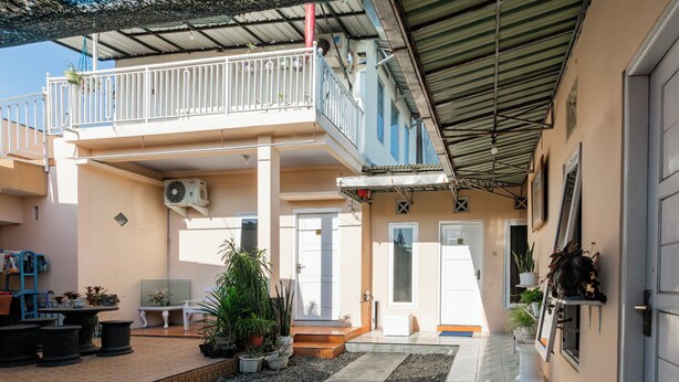 A two-story building with a balcony, potted plants, and a tiled patio area. - Hotel O Maluku Guest House (Blitar)