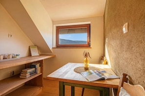 Een gezellig hoekje om te lezen, met een houten tafel, boeken, een vaas en een raam met uitzicht.