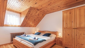 A wooden-framed bedroom with a sloped ceiling, a large wardrobe, and a radiator. - Suite Alder embraced by nature (Prevalje)