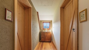 A narrow hallway with wooden doors and a window at the end. - Suite Alder embraced by nature (Prevalje)