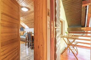 A wooden interior with a dining area, a sofa, and a television.