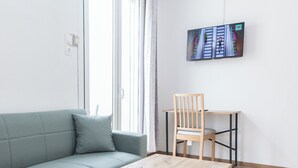 Ett modernt vardagsrum med en ljusgrön soffa, en trästol och ett träbord.