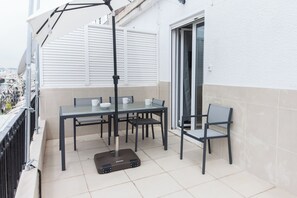 An outdoor patio with a table and chairs, a suitcase, and a patio umbrella. - Modern Comfort 1Bd Apt with Balcony (Athens)