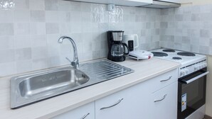 Ett modernt kök med en diskho i rostfritt stål, en kaffebryggare och en spis.
