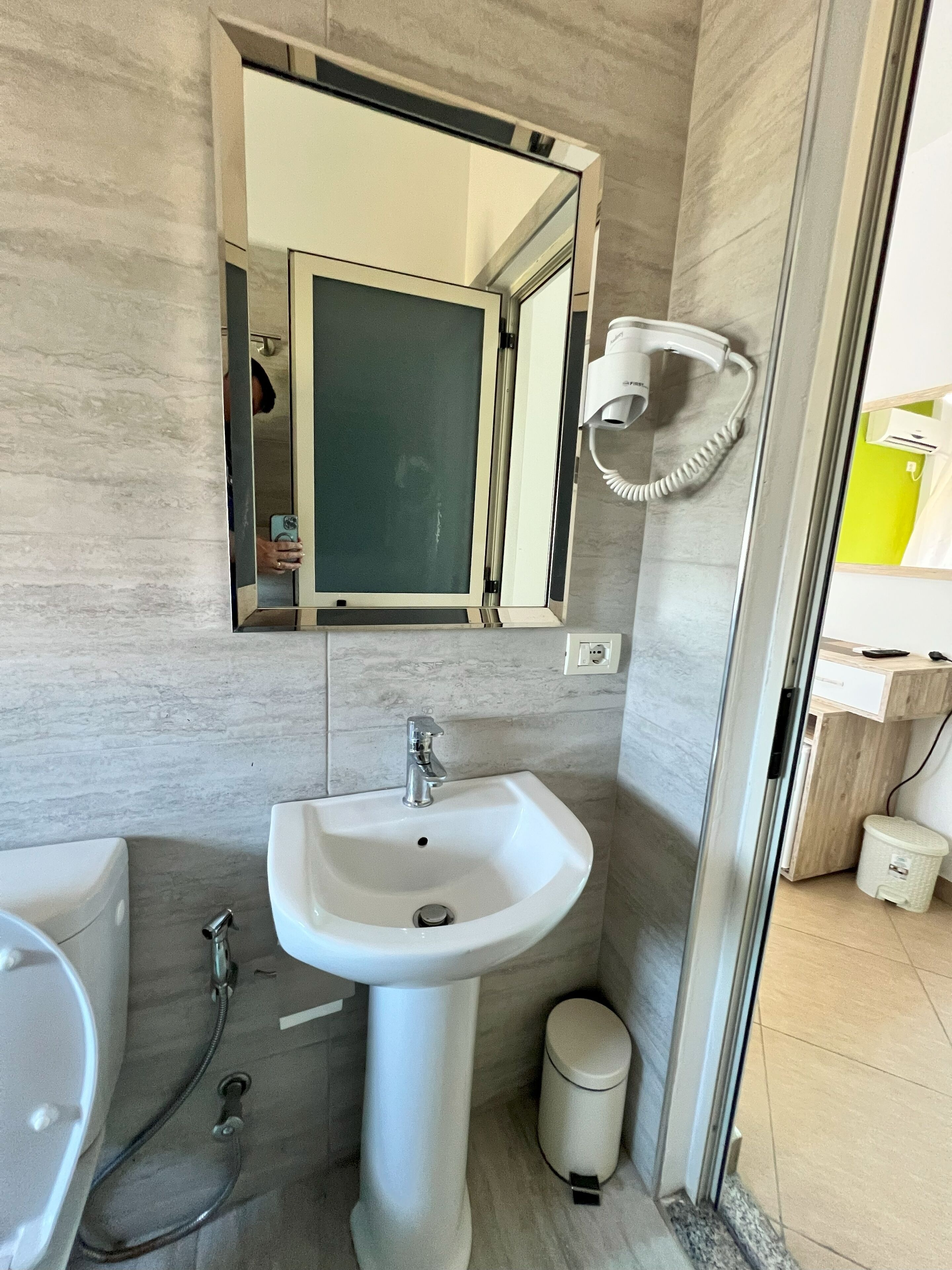 A bathroom with a white sink, a mirror, a hairdryer, and a toilet.
