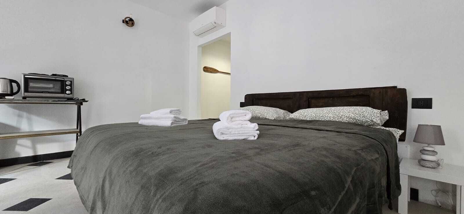 Una habitación de hotel con una cama, un microondas, una lámpara y un perchero para toallas.