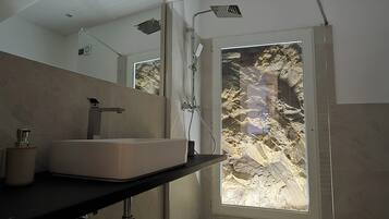 Une salle de bain moderne avec un grand miroir, un lavabo rectangulaire et une douche dotée d’une porte en verre.