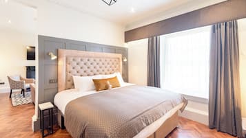 Une chambre à coucher moderne avec une tête de lit capitonnée, un grand lit, une table de chevet et une chaise.