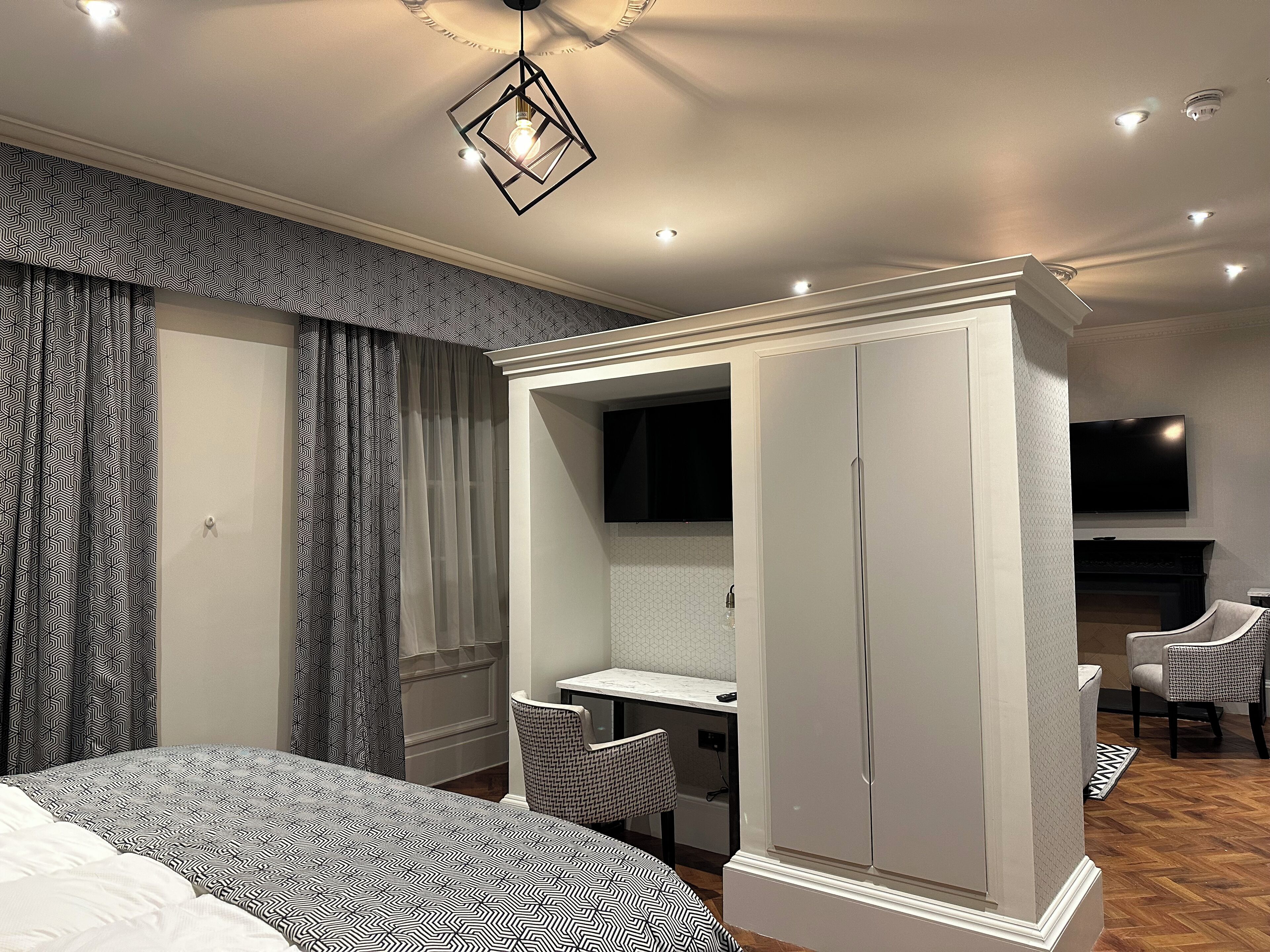 Ein modernes Schlafzimmer mit Bett, Schreibtisch, Kleiderschrank und Fernseher.