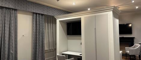 A modern bedroom with a bed, a desk, a wardrobe, and a TV.