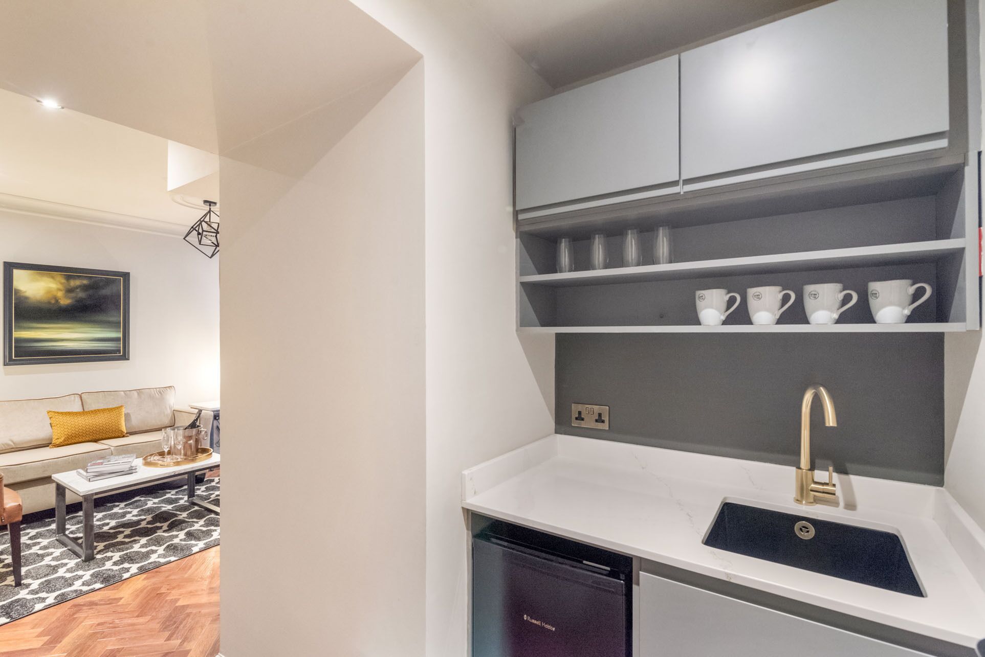 A modern kitchen with a built-in dishwasher, white countertops, and grey cabinets.