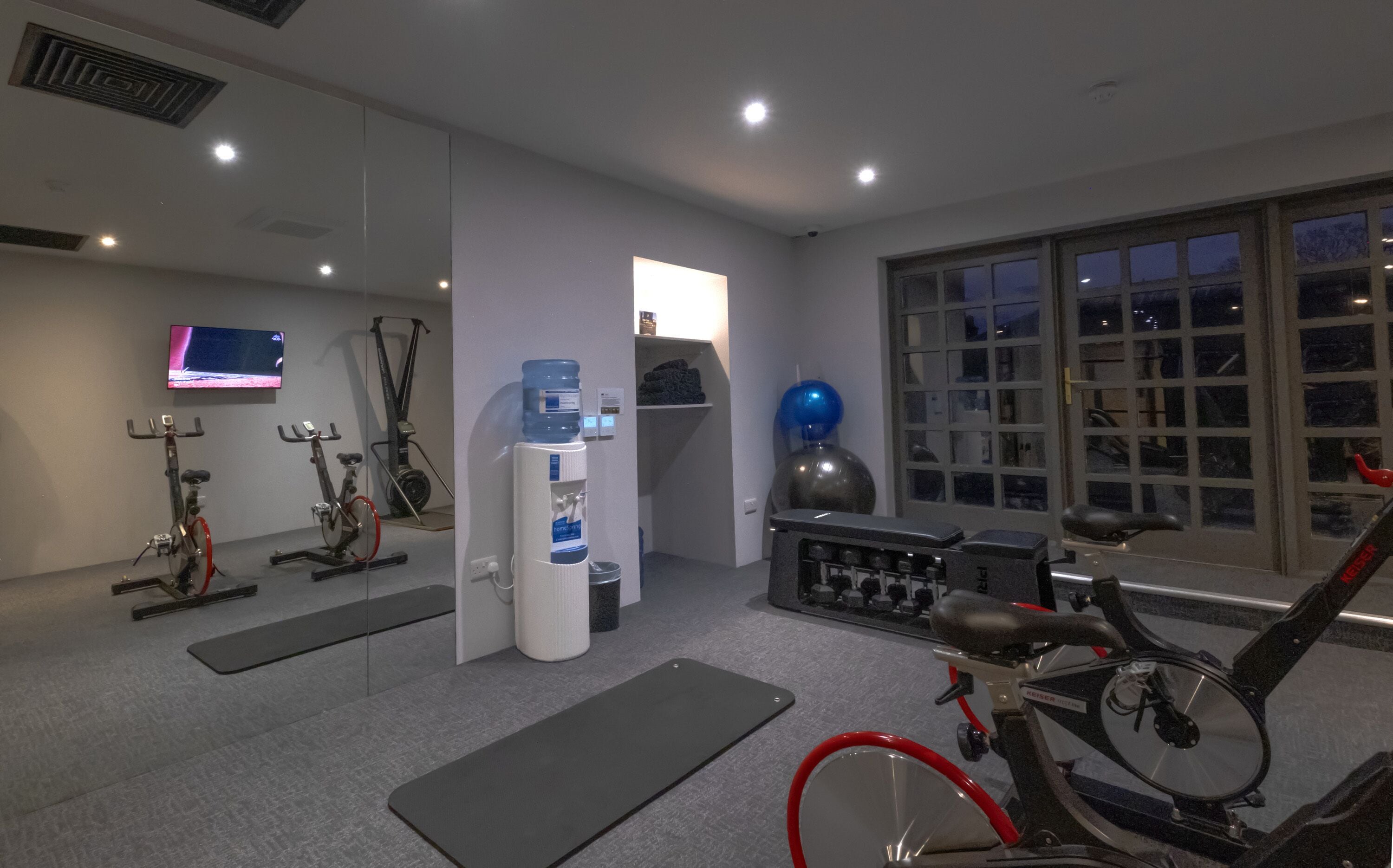Une salle de sport équipée de vélos d’exercice, d’un distributeur d’eau et d’une grande fenêtre.